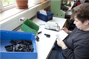 Verschiedene Zubehörteile und eine Montagebeschreibungen für Garagentore werden von einer Mitarbeiterin in Kunststoffbeutel verpackt