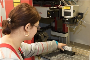 Eine Mitarbeiterin legt ein zu beschriftendes Produkt in den Laser ein