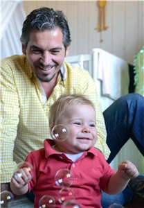 Ein lachender Vater spielt mit seinem kleinen Sohn mit Seifenblasen