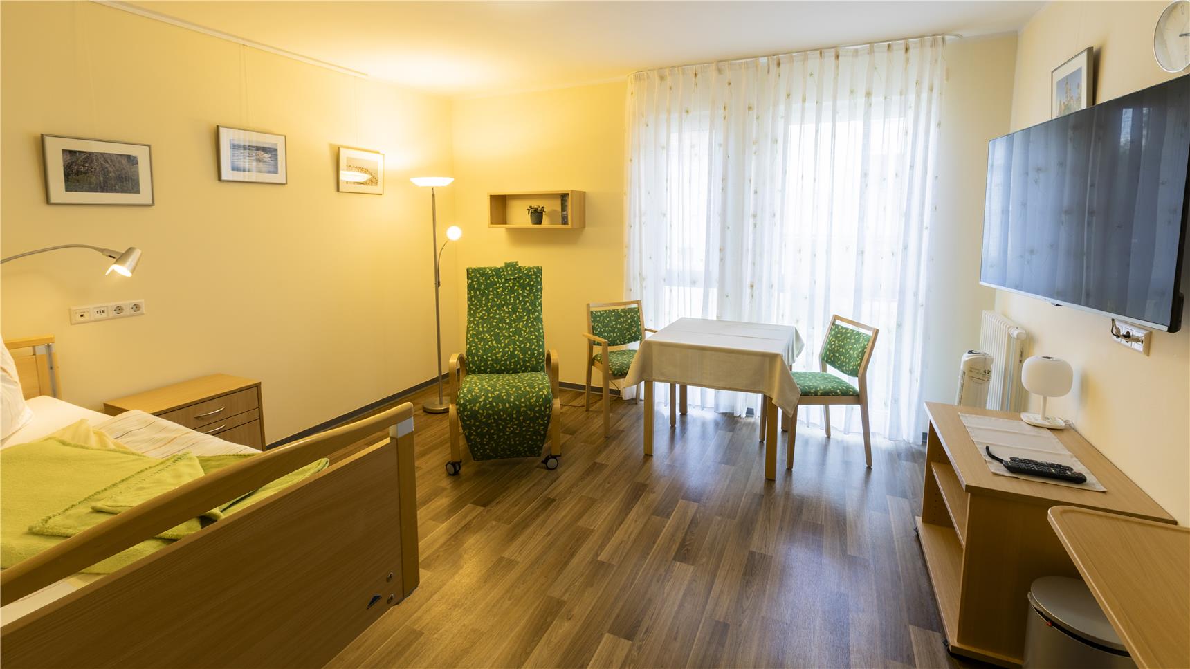 Zimmer für Hospizgäste mit Pflegebett und Sitzgruppe