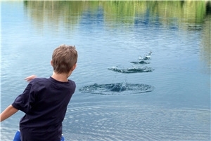 Junge wirft Steine in einen See