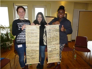 Drei junge Frauen halten Transparente mit Workshop-Ergebnissen