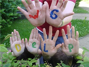 Viele Kinder halten ihre Hände vor die Kamera. Auf den Innenflächen haben sie die bunte Buchstaben 'WG Delp' geschrieben.