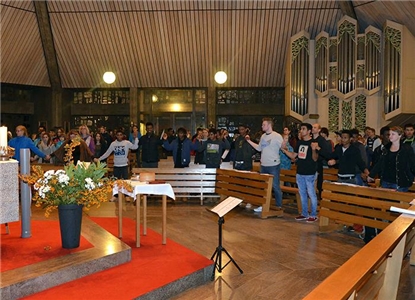 Wir sind zu Gast im Gottesdienst in Maberzell und blicken in die Teilnehmer. Alle fassen sich an den Händen und bilden eine große Schlange.