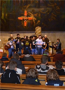 Eine Gruppe Jugendlicher steht vor dem Altar. Links und rechts begleiten 2 Jugendliche den Gesang mit Gitarren.