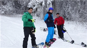 Drei Jugendliche stehen warm angezogen auf einer Schneepiste.