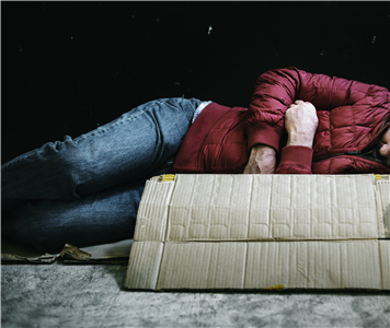 Obdachlose Person liegend auf der Straße