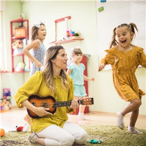 Erzieherin spielt Gitarre und Kinder tanzen