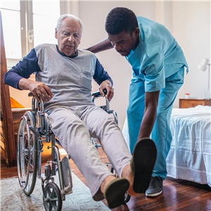 Pfleger hilft Mann mit dem Rollstuhl zu Hause