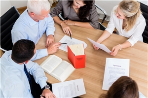 5 Personen sitzen um einen Tisch