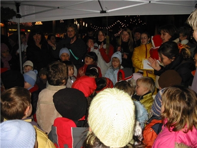 Viele Frauen und Kinder stehen auf dem Weihnachtsmarkt und singen