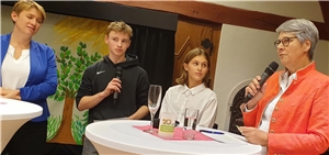 Zwei Frauen, ein Junge und ein Mädchen stehen an einem Tisch
