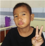Ein Junge mit einer operierten Lippe zeigt das "Victory"-Zeichen mit den Fingern