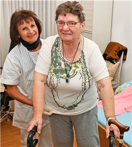 Altenpflegerin hilft Patientin beim Ankleiden