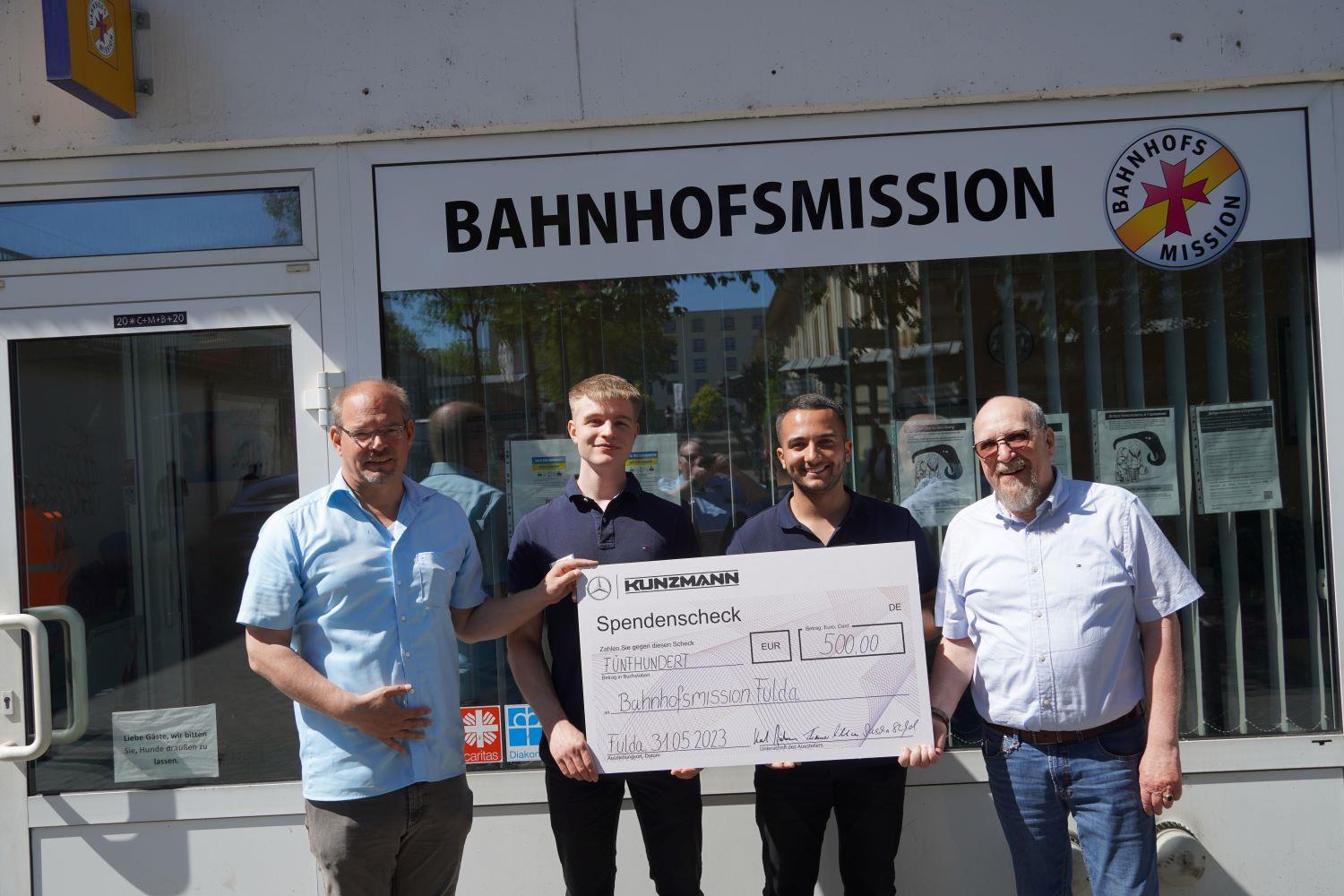 Gruppe hält Spendenscheck für Bahnhofsmission
