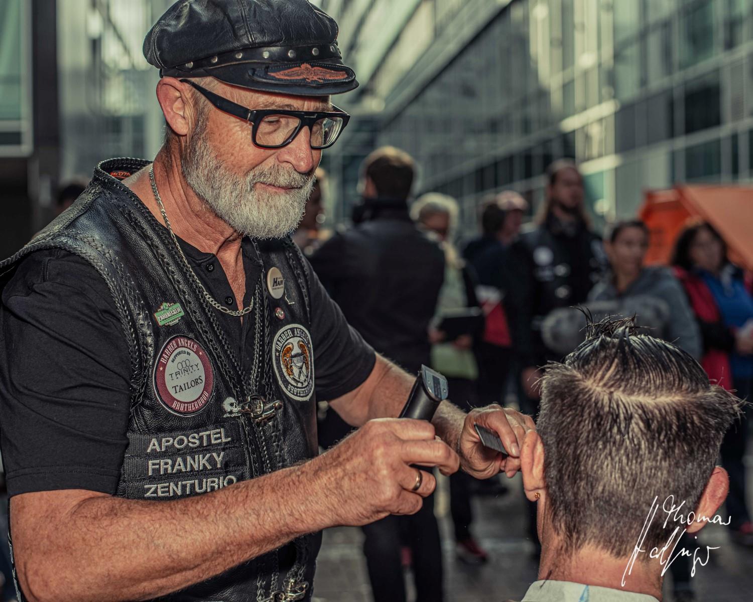 Älterer Herr mit Kutte schneidet im öffentlichen Raum Haare