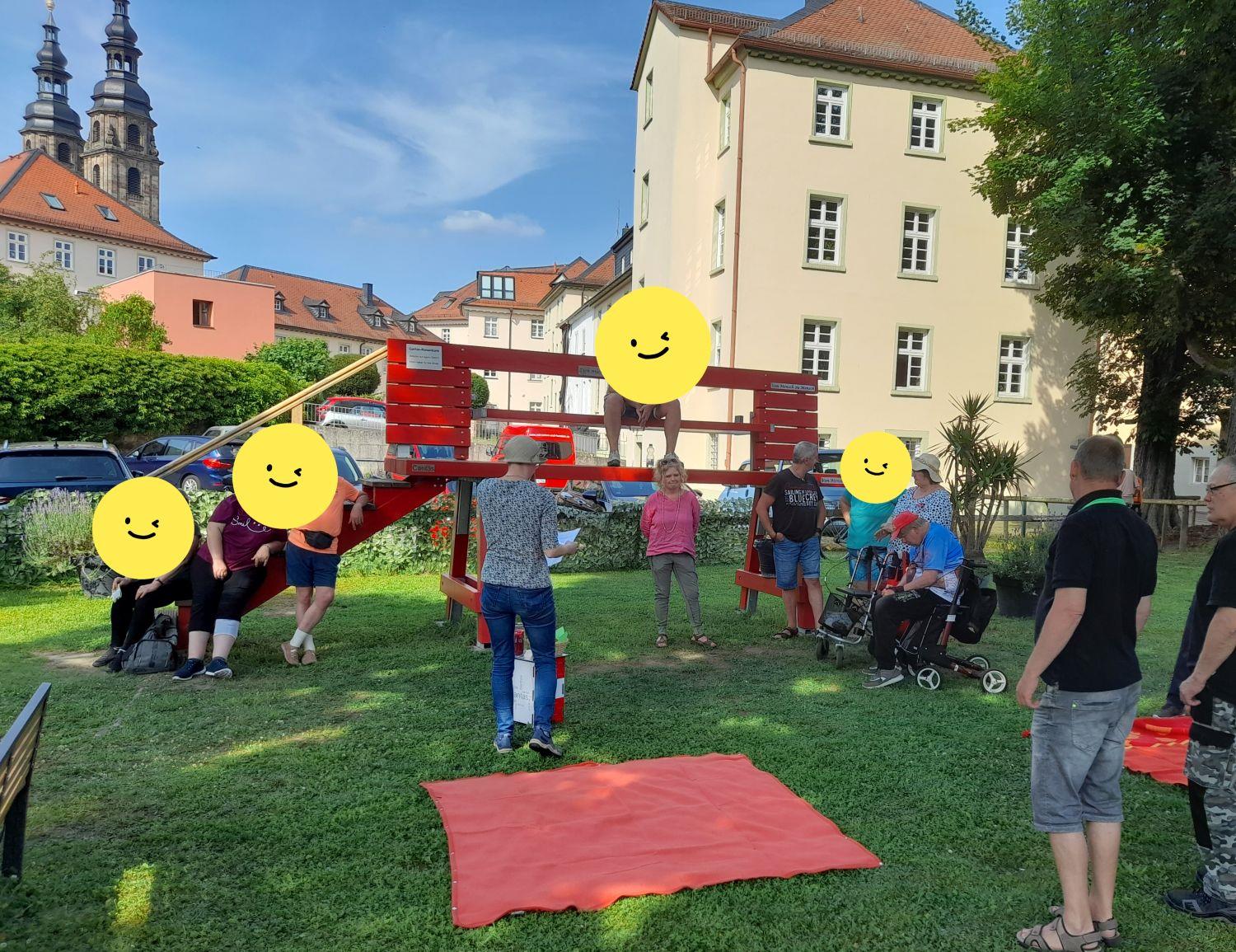 Picknickteilnehmer an der roten Caritasbank im Garten