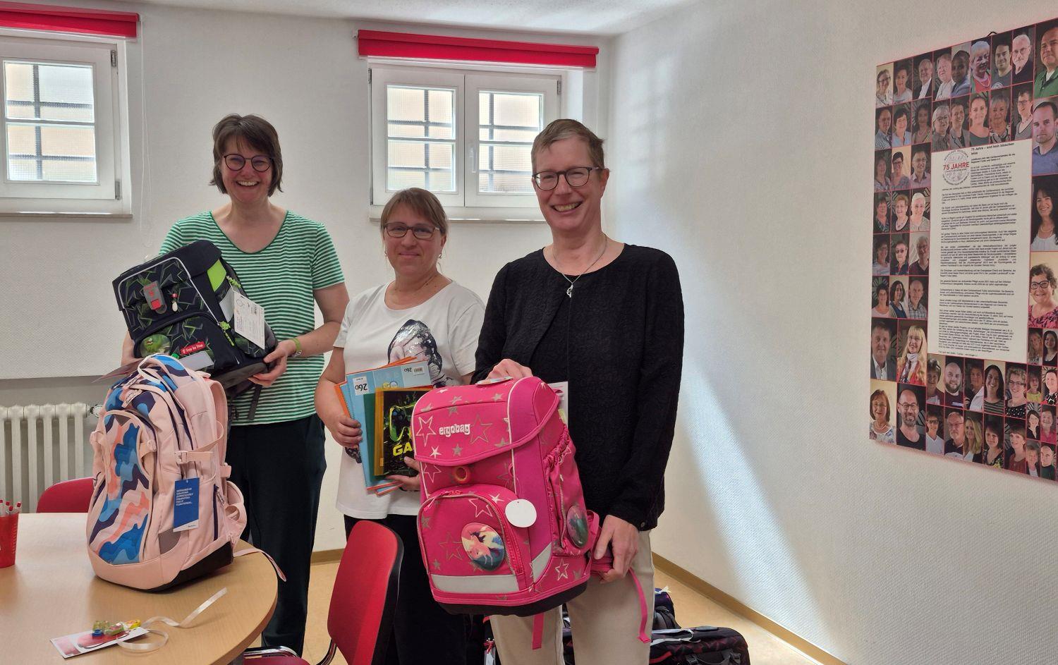 3 Frauen packen fröhlich Schulranzen 