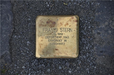 Wir blicken auf den Stolperstein von Franzi Stern, der auf dem Gehweg eingelassen wurde.