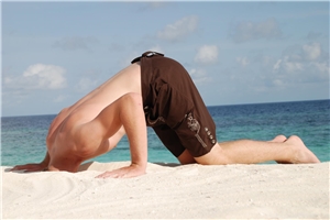Mann am Strand steckt Kopf in den Sand