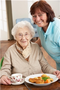 Seniorin und Pflegekraft, davor auf dem Tisch das Mittagessen