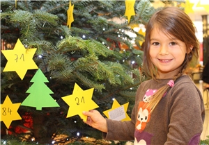 Kind beim Schmücken des Weihnachts-Wunschbaums