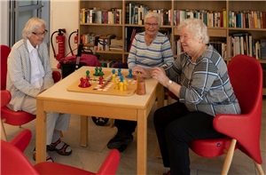 Drei Seniorinnen sitzen am Tisch und spielen Mensch ärgerd Dich nicht