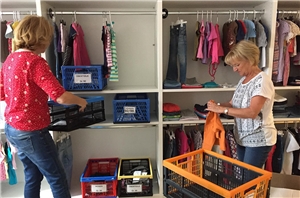 Helferinnen räumen Schränke im neuen Kinder-Kleiderladen ein