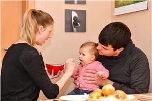 Junge Eltern füttern ihr Baby