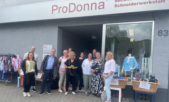 Das Bild zeigt viele Personen vor einem Geschäft stehend. 