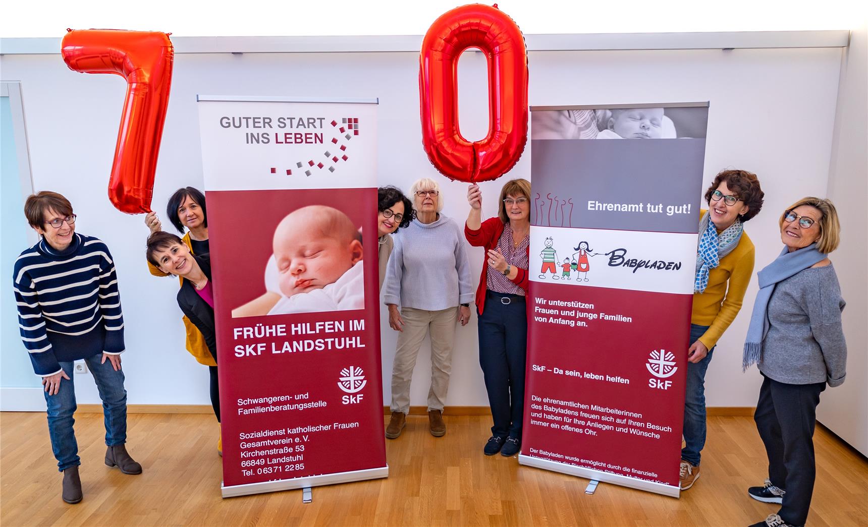 Mehrere Frauen stehen vor und hinter einem großem Plakat 