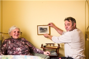 Hausmeister bringt Bild im Zimmer einer Seniorin an