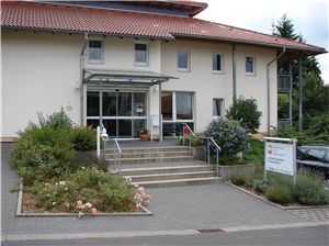 Eingang des Hauses Wir blicken auf eine breite Treppe und ein helles Foye der Einrichtung