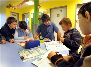Einige Schüler und Lehrer sitzen gemeinsam am Tisch und machen Aufgaben Einige Schüler und Lehrer sitzen gemeinsam am Tisch und machen Aufgaben
