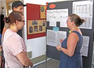 Eine Mitarbeiterin beantwortet vor einer Stellwand zwei Besuchern Fragen. Gruppenleiterin Christine Kern (rechts) steht mt zwei Besuchern vor einer Stellwand mit Infos und gibt dazu eine Erklärung.