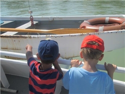 Zwei Jungen sind auf einem Schiff. Ein Junge zeigt auf das Rettungsboot.