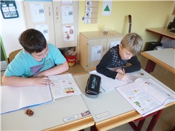 Zwei Jungen sitzen an ihren Schreibtischen und machen Hausaufgabe.