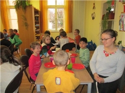 Kinder aus der HPT und dem Kinderhort sitzen gemeinsam zum Essen und Trinken an Tischen.