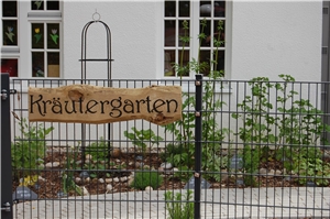 Holzschild beschriftet mit Kräutergarten