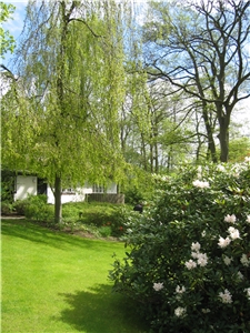 Ansicht des Kinderhaues mit einem kleinen Teil des Gartens, bl�hender Rhododendron im Vordergrund