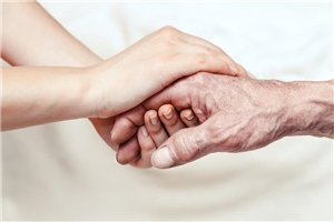 Hand einer alten Frau wird zwischen den Händen gehalten