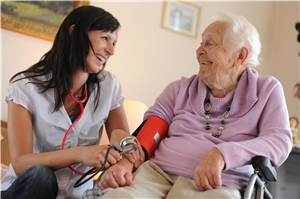 Pfleger beim Blutdruckmessen bei einer alten Dame