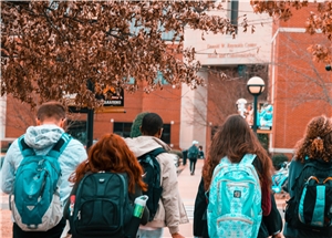 Vier Studierende laufen im Herbst über den Campus