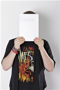 Junger Mann mit Schild vor dem Kopf, auf dem 'Loser' steht