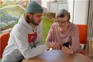 Jakob erklärt einer Seniorin die Funktionen des Smartphones