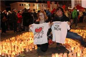 Zwei Jugendliche mit Shirts in der Hand im Kerzenmeer