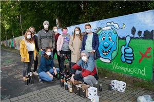 Gruppe Jugendlicher vor einer mit Graffiti bemalten Wand