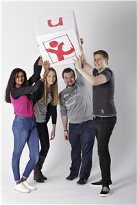 Vier junge Menschen halten Würfel mit youngcaritas-Logo hoch