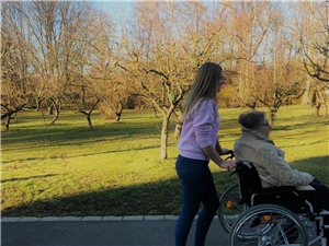 Jugendliche schiebt Seniorin in Rollstuhl