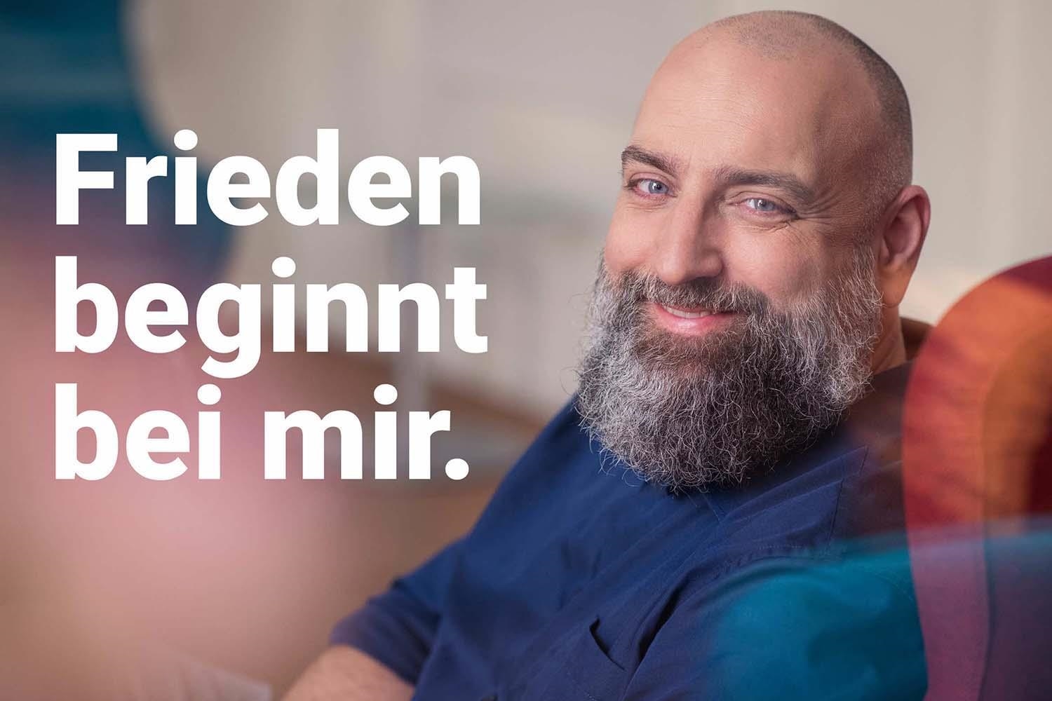 Ein Mann mit Bart lächelt in die Kamera. (Deutscher Caritasverband e.V.)